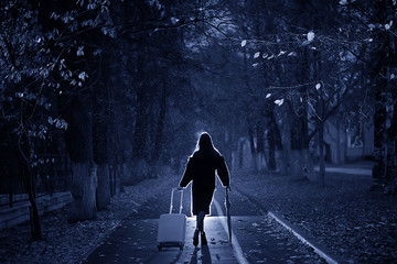 night the girl is walking with an umbrella and a suitcase in the autumn park, the concept of...