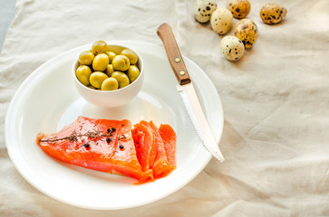 Slices of Salted Raw fish fillet with olive, quail eggs on white plate. Products good for healthy hair. Selective focus