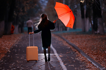 night the girl is walking with an umbrella and a suitcase in the autumn park, the concept of...