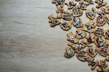 Christmas gingerbread decorated with chocolate and sprinkles on the wooden background with copy space. Preparation christmas cookies.
