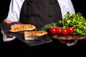 Chef presenting two countertops with salmon and vegetables