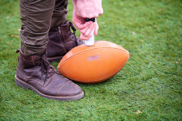 man pumping air into american football ball