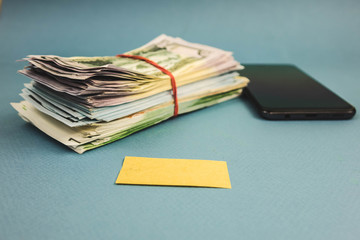 war of money and phone lying on a blue background.