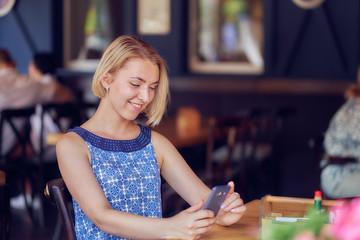 young woman in a restaurant using a phone uses social network app