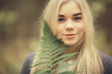 eco concept girl portrait fern, young adult model blonde, green leaf on face