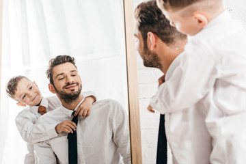 cheerful boy embracing bearded dad in white shirt at home © LIGHTFIELD STUDIOS