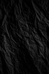 Dark black crumpled paper close up texture background