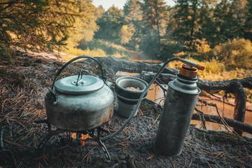 Kettle, gas burner and silicone mug close-up. Hiking in the forest.