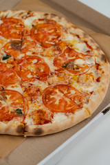 Pizza Margherita with cheese and tomatoes in a cardboard box close up