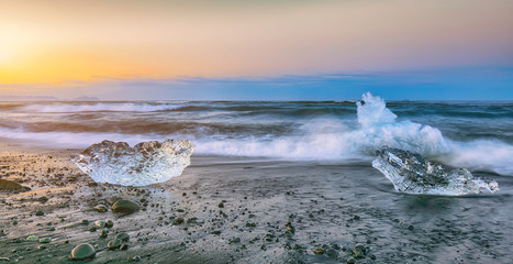 Incredible pieces of the iceberg sparkle on famous Diamond Beach at  Jokulsarlon lagoon during sunset