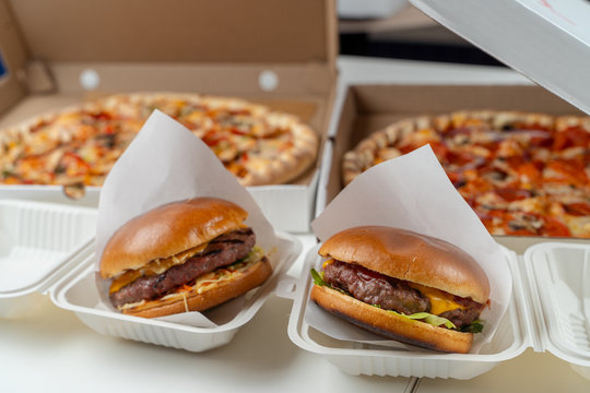 Unhealthy snacks delivery in boxes: italian margherita and chicken pizza, beef burgers with cheddar cheese