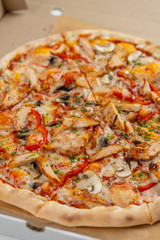 Hot chicken pizza with mushrooms and bell pepper with a thick crust in a delivery box