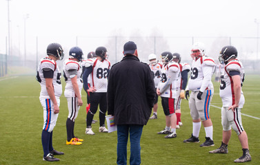 american football players discussing strategy with coach