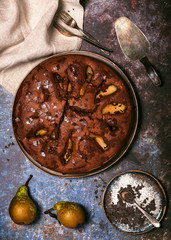 Delicious homemade autumn chokolate fruit pie with some fresh pears on dark rustic background. Top view.