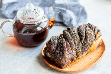  Poppy seed roll with butter and tea. Baking with poppy seeds. The work of the baker. Baking rolls with poppy seeds and pies in the kitchen. Bakery, cook together.