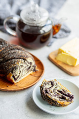  Poppy seed roll with butter and tea. Baking with poppy seeds. The work of the baker. Baking rolls with poppy seeds and pies in the kitchen. Bakery, cook together.