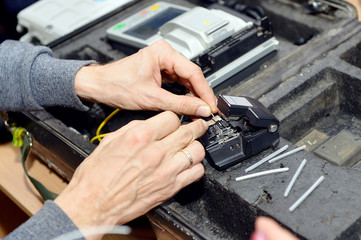 An optical fiber welder works with a fiber cleaver. A technician cuts and fusion fiber optic cables.