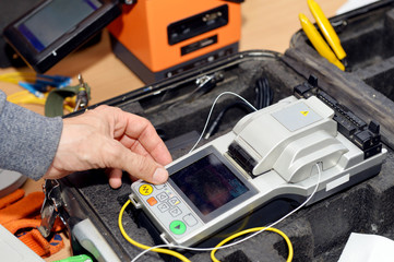 A technician is welding a fiber optic cable using a welding machine.