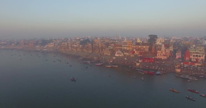 Drone shot flying away from the beautiful, crowded harbor and coastline on the river in the city of Varanasi, India. 