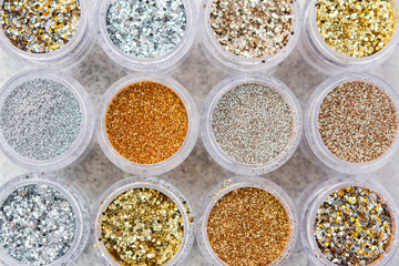 Beautiful glitter in golden and silver shades in small glass jars, top view, selective focus