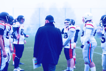 Obraz premium american football players discussing strategy with coach
