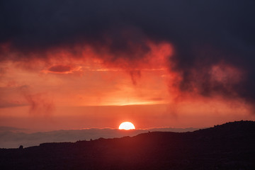 Spectacular blood red and orange sunset with overcast sky