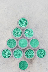 Christmas tree made of glitter in trendy turquoise green shades in small glass jars, top view selective focus