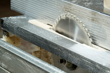 Saw blade, woodworking machine closeup. Furniture manufacturer. Table with shelves of chipboard.