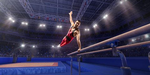 Male athlete doing a complicated exciting trick on parallel bars in a professional gym. Man perform...