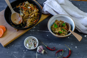 A pan and plate of homemade pilaf with garlic and  chilli pepper