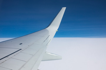 Obraz premium View through the window of an airplane wing against the blue sky.