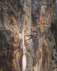 A man is walking along a stretched sling. Highline in the mountains. Man catches balance. Performance of a tightrope walker in nature. Highliner on the background of the mountains.