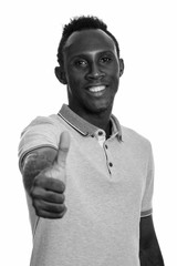 Young happy African man smiling and giving thumb up