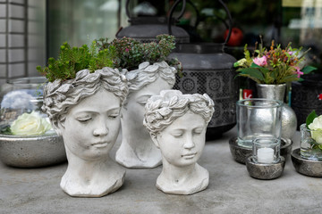 Gypsum flower pot in the shape of antic head of goddess with growning out green flowers. Stylish home decor