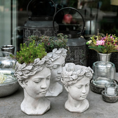 Gypsum planter, flower pot in the shape of antic head of girl with growning out green flowers. Stylish home decor
