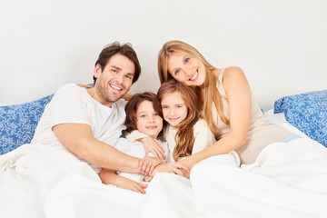 Fototapeta premium Glückliche Eltern und zwei Kinder beim Kuscheln