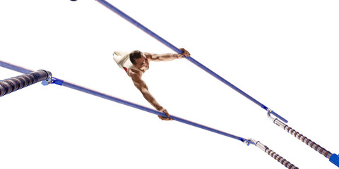 Male athlete doing a complicated exciting trick on parallel bars on white background. Isolated Man...