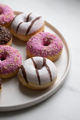 Colorful donuts on marble background with copy space