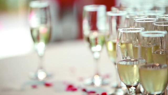 Elegant champagne glasses standing in a row and red roses petals. Wedding anniversary 