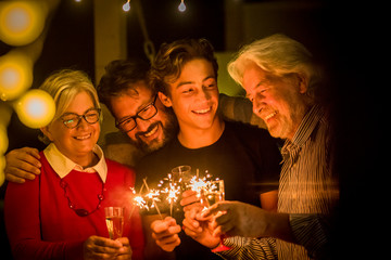 group of two seniors and an adult and a teenager together having fun with sparlers the new year to celebrate - happy family with lights
