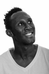 Face of young happy African man smiling and thinking