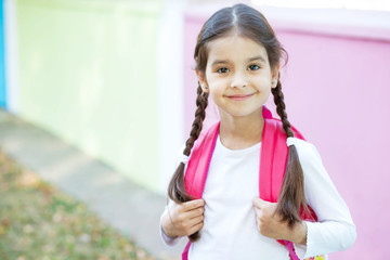 Happy latin school girl with a briefcase outdoor