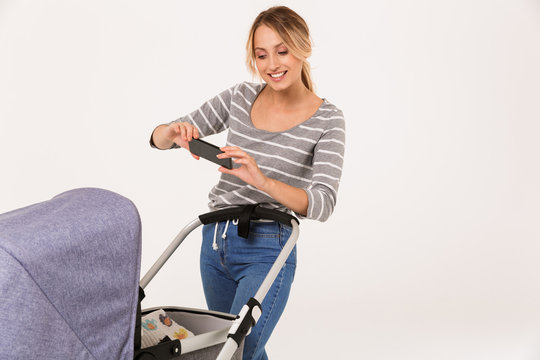 Image of smiling nice woman taking photo her baby in stroller