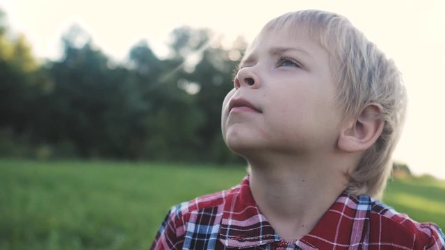 little boy portrait concept happy family. boy blond son looking up portrait slow motion video in nature in a plaid shirt sunlight glare happy lifestyle childhood concept