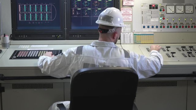 engineer sits in a chair and controls a cargo operations control panel