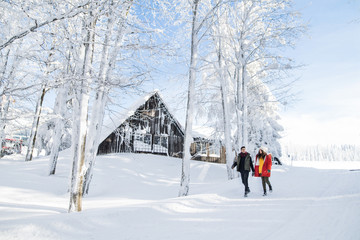 Young couple walking outdoors in snow in winter forest.