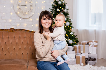 christmas and family concept - mother and cute little baby girl daughter near decorated christmas tree