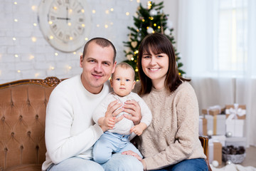 christmas and family concept - young family with cute little baby daughter near decorated christmas tree