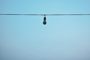 Wires and bulbs in blue sky background.