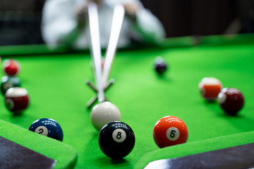 Man's hand and Cue arm playing snooker game or preparing aiming to shoot pool balls on a green...